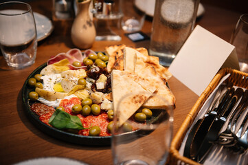 A light snack and appetizer on table. Served dinner table in cafe interior. Event festive dinner. Delicious dishes in restaurant. Serving table with food, birthday setting. Side view. Setup table.