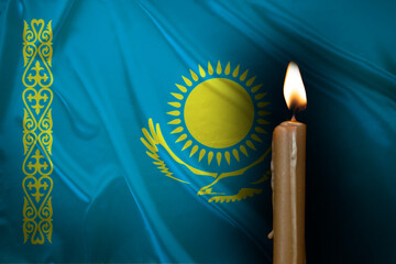 mourning candle burning front of Kazakhstan flag, Victims of cataclysm or war concept, memory of heroes served country, grief over loss, national unity in challenging times, state's history