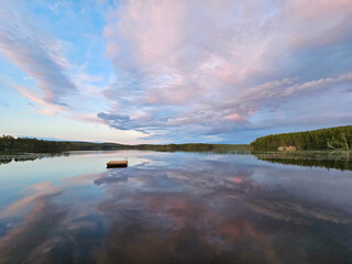 Swimming island in Sweden on a lake at sunset. Clouds reflected in the water.
