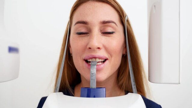Close-up of woman's face with head positioned in cephalometric panorama x-ray machine. Female patient stands in dental x-ray machine for dental radiography. Woman making panoramic shot of the jaw.