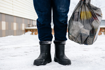 Man taking out the trash outside in winter. - obrazy, fototapety, plakaty