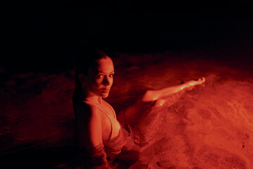 Elegant lady submerged in a serene lagoon during nocturnal hours, displaying grace, allure amidst...