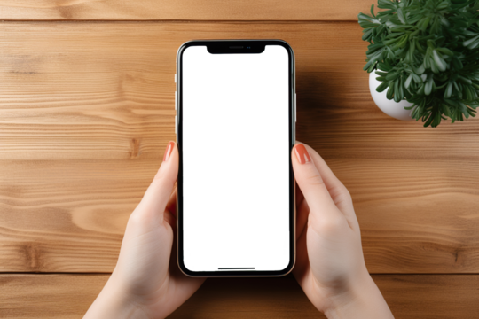 Vista superior de mano de mujer sosteniendo teléfono inteligente con pantalla vacía para introducir imágen y texto sobre fondo de mesa de madera.