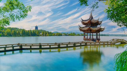 Serene Lakeside Pagoda at West Lake, Hangzhou, China with Lush Greenery and Wispy Clouds