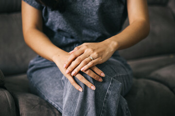 Portrait of a wife wearing gold wedding ring while sitting on sofa alone