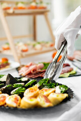 woman hands of a waiter prepare food for a buffet table in a restaurant