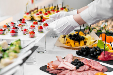 woman hands of a waiter prepare food for a buffet table in a restaurant
