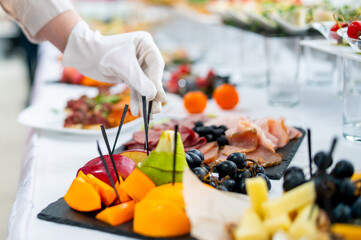 woman hands of a waiter prepare food for a buffet table in a restaurant