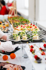 woman hands of a waiter prepare food for a buffet table in a restaurant