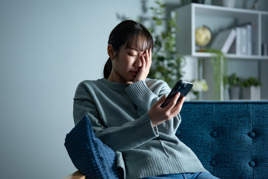 携帯を持ち落ち込む女性