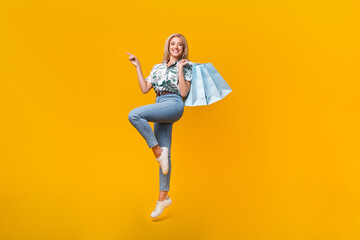 Fototapeta na wymiar Full length photo of attractive woman wear blouse hold shopping bags indicating at offer empty space isolated on yellow color background