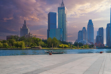 Serene Urban Waterfront Scene with Rowboat and Sunset Skyline, Calm Waters, and Modern City Backdrop