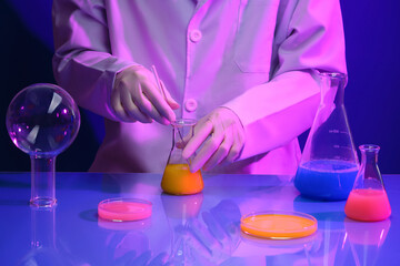 Male or female scientist is stirring the chemical liquid inside the erlenmeyer flask. Glass petri...