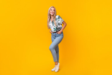 Full length photo of lovely positive woman wear stylish blouse denim pants look at sale empty space isolated on yellow color background