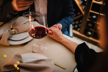 Romantic date by candlelight at night. Proposal hand and heart. Hands man and woman hold glasses. Couple in love drinking wine. Dinner setup table for couple. Will you marry me. She said yes. Top view - obrazy, fototapety, plakaty
