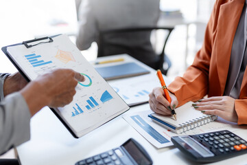 Meeting of business people pointing at graph. Group of businesspeople discussing together at a meeting.