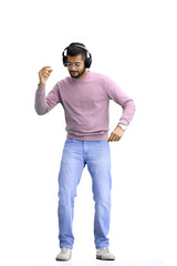 A man, on a white background, in full height, listening to music with headphones