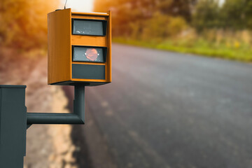 A radar-equipped speed camera monitors the traffic on a road, flashing a yellow light when it...