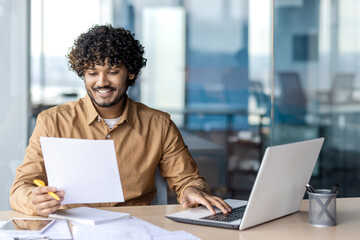 Successful and joyful financier accountant works with papers and documents inside office at...