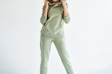 Horizontal studio photo for sports clothing sale. Model Showcasing a Stylish and Comfortable Outfit Perfect for Everyday Wear. A Girl wears a light green hoodie and pants © AlexGo