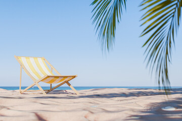 3D rendering of a striped beach chair on sand with palm leaves overhead, summer relaxation concept.