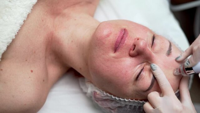 Close-up of the cosmetologist doing hydrafacial treatment on woman face in beauty clinic