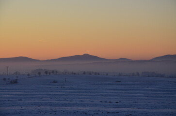 Foggy winter landscape with church and village in the background.