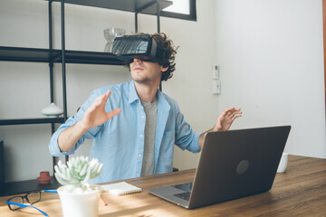 Creative designer excited watching on VR glasses headset. Man having virtual reality experience. Touching air while playing video game or simulation world