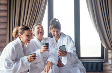 Obraz premium Three young smiling women in white bath robes on spa procedure