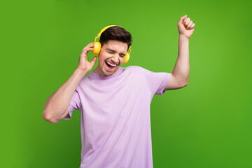 Portrait of ecstatic person wear violet t-shirt clenching fist touch headphones listen pop music...