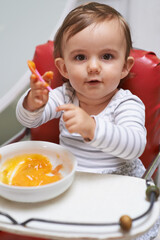 Baby, high chair and food in bowl for meal, nutrition or healthy porridge with spoon at home. Portrait of young cute little child, kid or toddler playing with snack for hunger, vitamins or nutrients