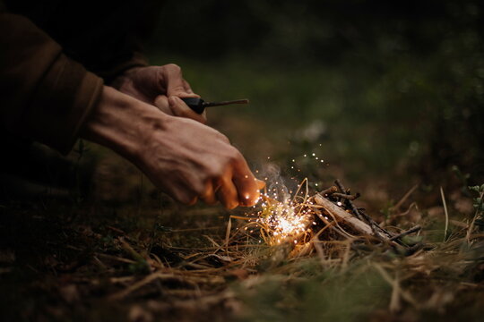 Man outdoors makeing fire by flint. Flamethrower. Survival in the wild