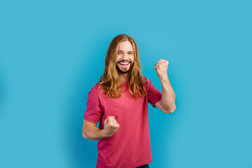 Portrait of satisfied glad young man toothy smile raise fists rejoice triumph isolated on blue color background