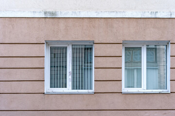 Two white PVC double casement windows. Closed blinds.