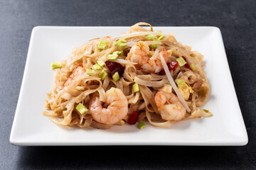 Pad Thai with shrimp and vegetables on black slate background