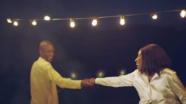 happy african american couple dancing together at party - people on summer night celebrating love and joy