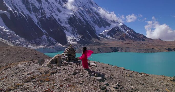 Fairylike female roams wearing pink dress at Manang Nepal. Drone shot, World's Highest Altitude Tilicho Lake Annapurna Mountain Circuit, cinematic movie shooting 4K