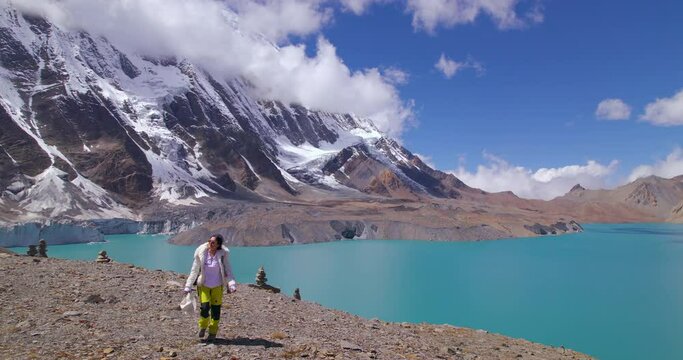 Tilicho Lake Manang Nepal, female tourist treks World's Highest Altitude Lake, Annapurna Mountain landscape drone shot, clouds, snows, nature, sunny weather, blue lake 4K