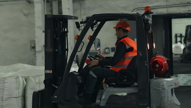 Inventory management, Pallet storage, Safety regulations. Warehouse worker is actively using forklift loader to manage placement of pallets.
