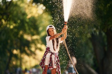 Flow of water, having fun. Young girl in casual clothes is in the public park outdoors