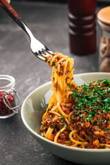 Eating appetizing spaghetti bolognese with herbs