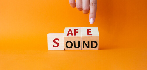 Safe and Sound symbol. Businessman hand points at cubes with words Safe and Sound. Beautiful orange background. Business and Safe and Sound concept. Copy space