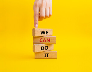 We can do it symbol. Concept words We can do it on wooden blocks. Beautiful yellow background. Businessman hand. Business and We can do it concept. Copy space. - obrazy, fototapety, plakaty