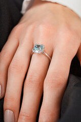 Beautiful female hand with gold ring with diamonds and emerald on gray background