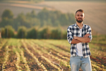 With arms crossed. Man is on the agricultural field, conception of work and harvest
