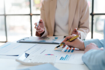 Meeting of businesswomen pointing at graph. Group of businesspeople discussing together at a meeting.