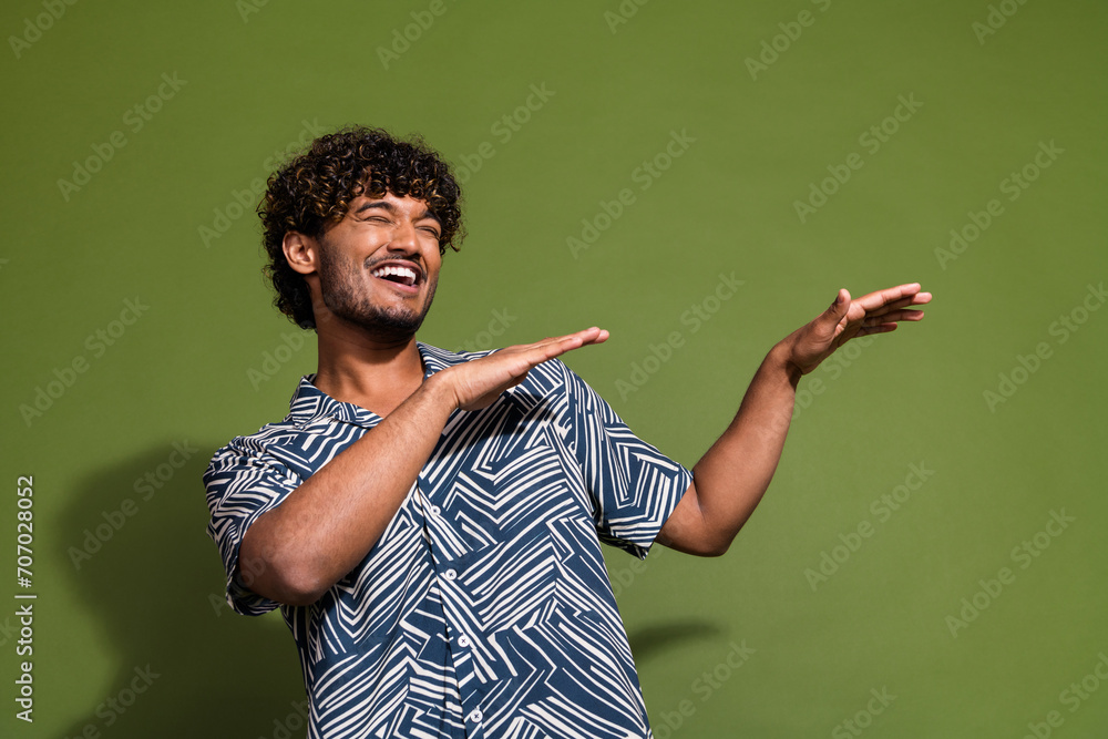 Wall mural Photo of young carefree indian guy wear shirt dance raised hands just chill at summer late night party isolated on khaki color background