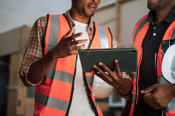 African American male shares insights with colleague on tablet in woodwork factory