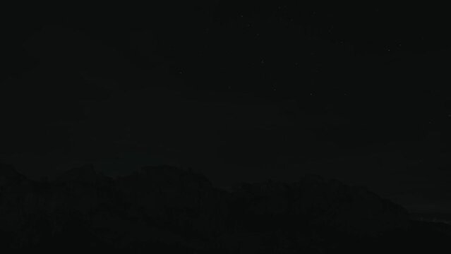 Timelapse video of sky with stars during night time near massive climbing rock.