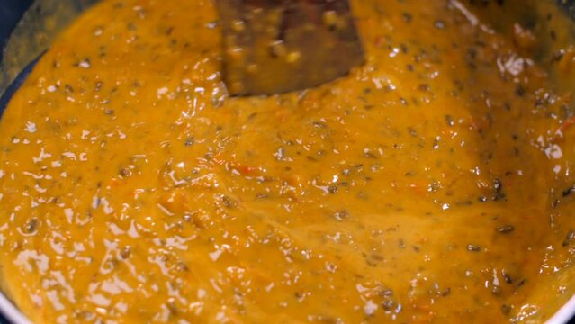 Closeup shot of cooking dal makhani on a gas stove - healthy Indian food  home-cooked food  homemade  vegetarian food. Stirring the hot dal curry with a wooden spatula in a nonstick pan